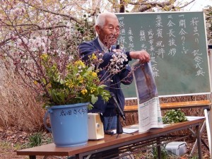 河津桜の花の元での記念式典　山長の飯田さんが経過報告 